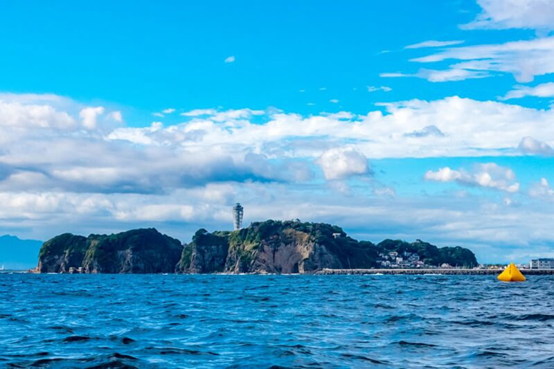 湘南・江ノ島とマリンスポーツのサップヨガをしている人と海